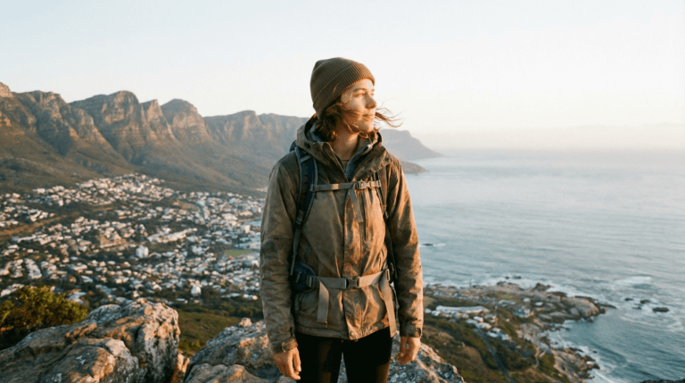 Solo backpacker overlooking a coastal city at sunrise, representing freedom in the best places for solo backpacking in 2026